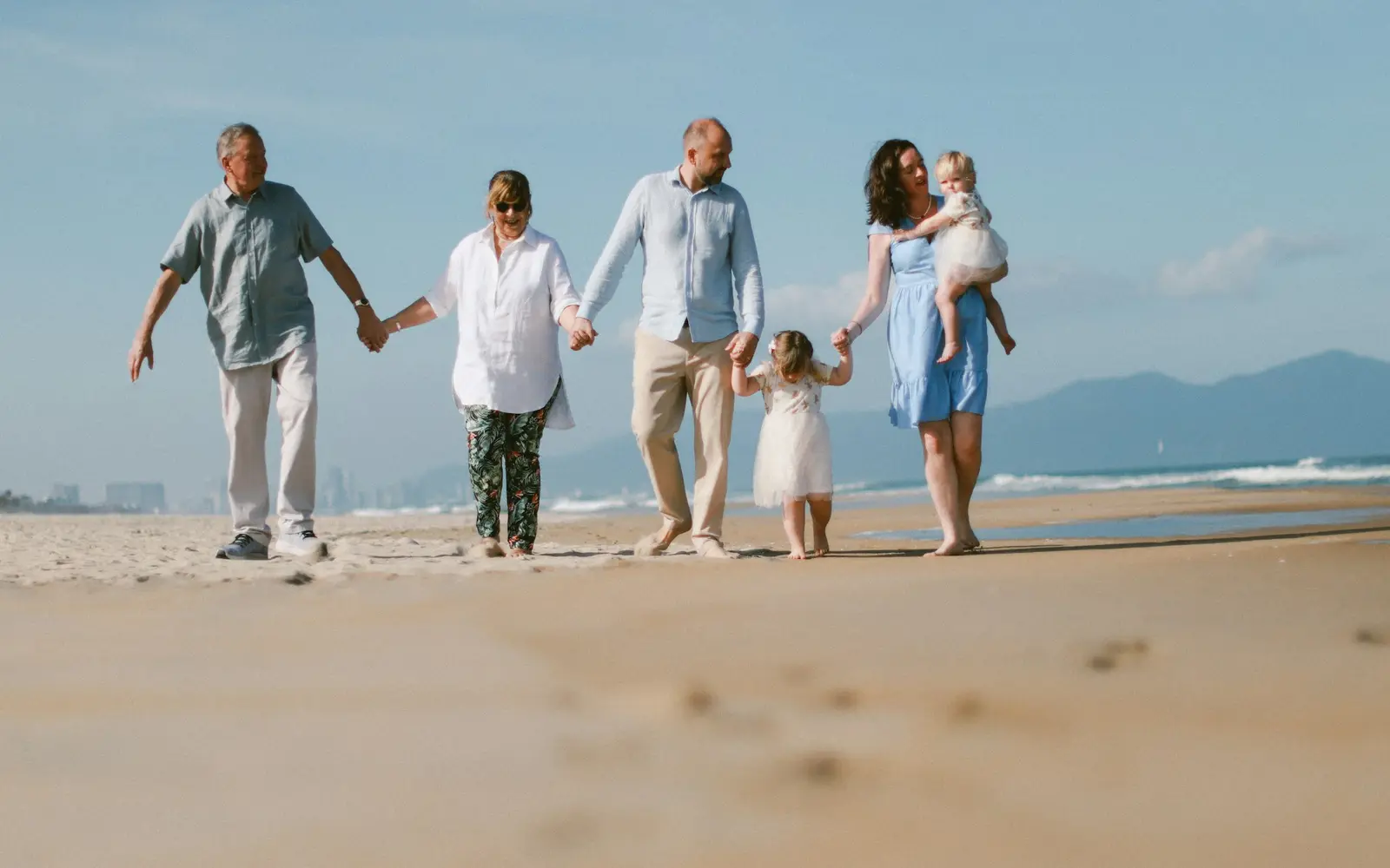 Three generations of a family walking along a beach