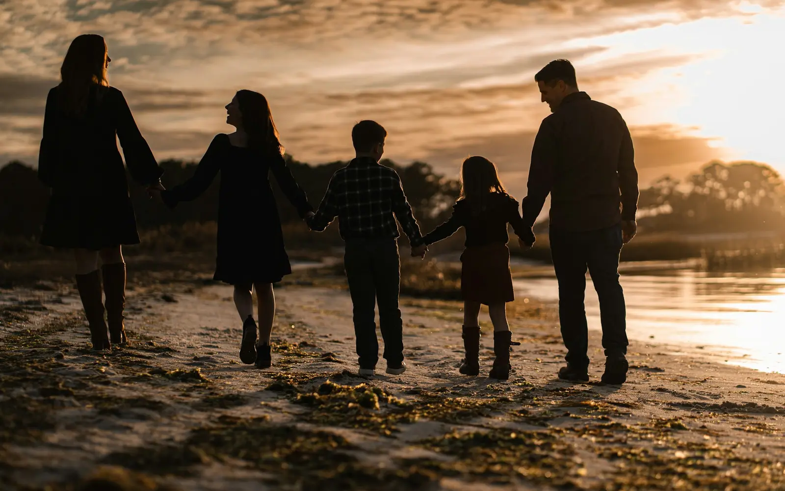 A family walking hand in hand along a beach at sunset